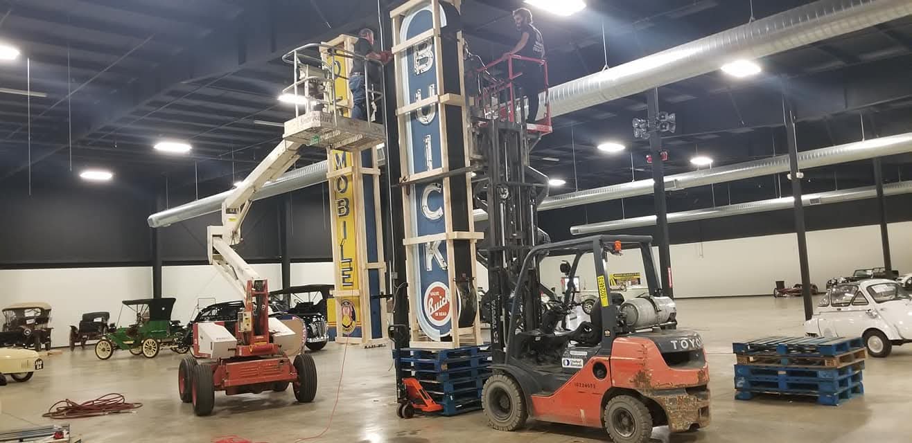Crew crating a vintage neon Buick dealership sign in the warehouse